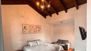 A bedroom with a bed, a sofa, a chandelier, and artwork on the wall. - Casa Don Pancho (Ciudad Vieja)