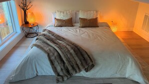 Ein Schlafzimmer mit einem großen Bett, einem Nachttisch mit Lampe und einem Fenster.