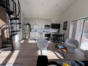 A modern kitchen with white cabinets, stainless steel appliances, and a dining area with a round table and chairs.