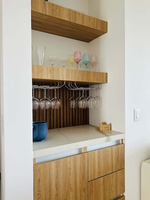 A kitchen with wooden cabinets, a countertop, and a wine rack holding glasses. - Wake Up to the Ocean Exclusive Luxury Escape (Tárcoles)