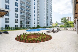 Um edifício moderno com várias varandas, piscina e espreguiçadeiras.