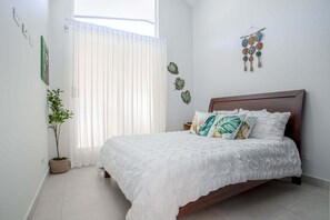 Een slaapkamer met een bed, een kamerplant en decoraties aan de muur.
