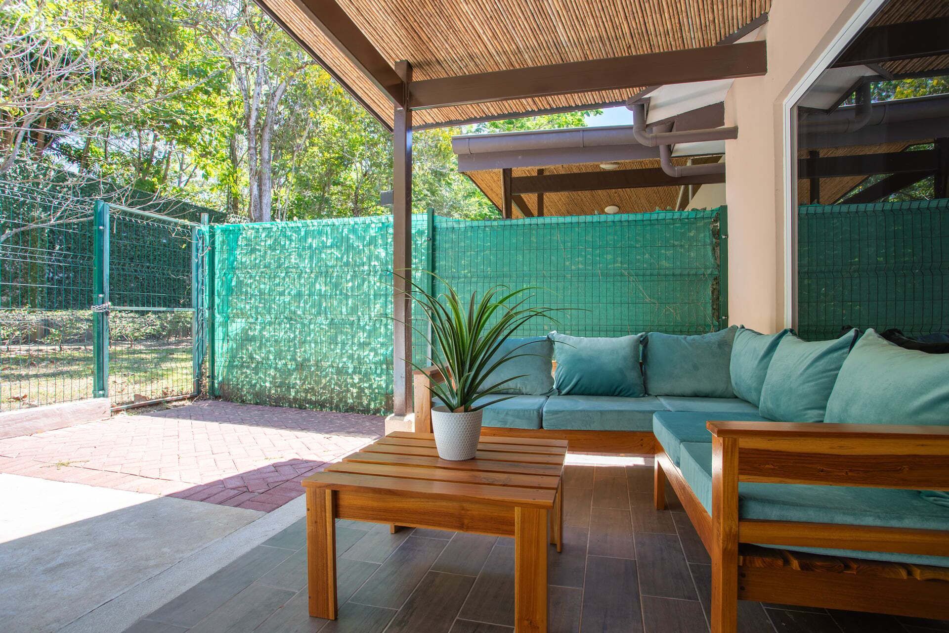 Un espacio al aire libre con un banco de madera, un sofá y una planta en maceta.