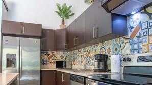 Una cocina moderna con electrodomésticos de acero inoxidable, un salpicadero con diseño y una planta en maceta.