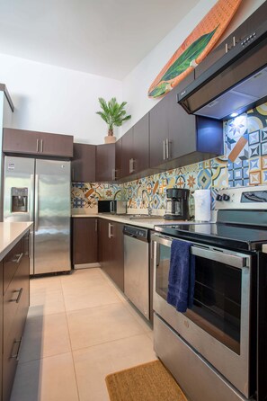 A modern kitchen with stainless steel appliances, a patterned backsplash, and a potted plant. - Private Pool & Tropical Style, Minutes From the Beach (Jacó)