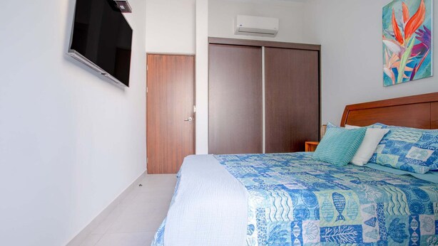 Un dormitorio con cama, armario, aire acondicionado y un cuadro en la pared.