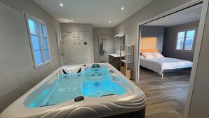 Une salle de bain moderne équipée d’un jacuzzi, d’une douche et d’un meuble-lavabo.