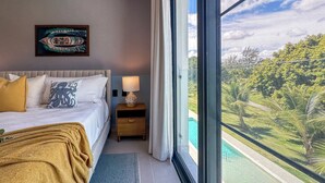 Ein Schlafzimmer mit Bett, Nachttisch und Blick auf einen Swimmingpool.