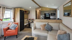 A compact living space with a kitchenette, a sofa, a chair, and a dining area. - 26 Ocean View (Llwyngwril)