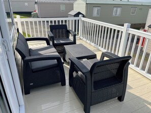 Una terraza con muebles de mimbre y barandal blanco.