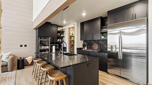 Una cucina moderna con isola centrale, elettrodomestici in acciaio inossidabile e sgabelli da bar in legno.