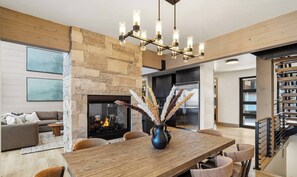 Un salon moderne avec une cheminée, une table à manger et un escalier doté d’une rampe.