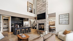 Un soggiorno moderno e open space con cucina, zona pranzo e camino.