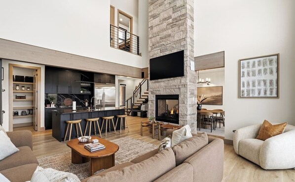 A modern open-plan living space with a kitchen, dining area, and a fireplace.