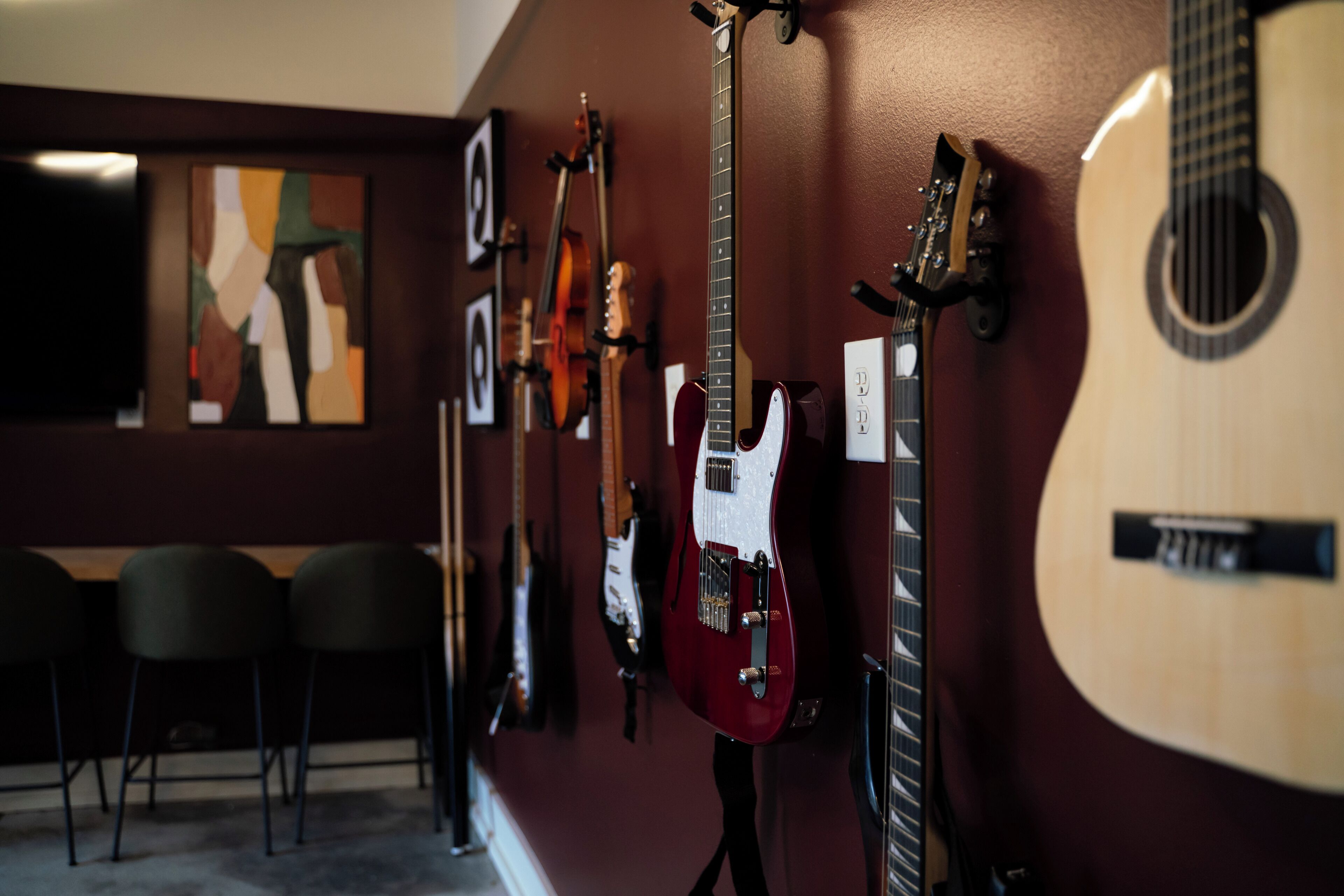Un mur orné de différentes guitares et d’un tableau.