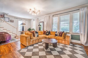 Una sala de estar con un sofá modular, una mesa de centro redonda y una escalera.