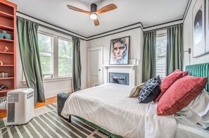 Un dormitorio con una cama, ventilador de techo, chimenea y estantería.