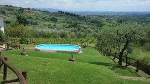 A swimming pool surrounded by a well-maintained lawn, with a view of distant hills and a clear sky. - Ciclamino House: Pool, view, wifi, lucca, Tuscany (San Gennaro)