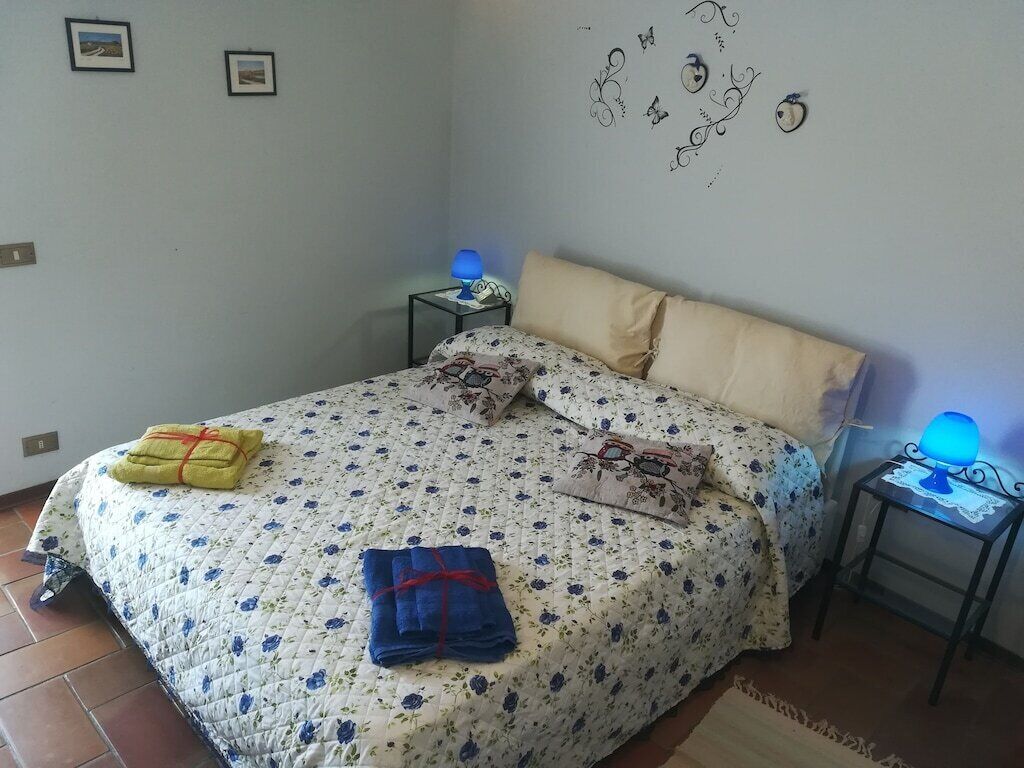 A bedroom with a bed, two bedside tables, a lamp, and a wall decoration.