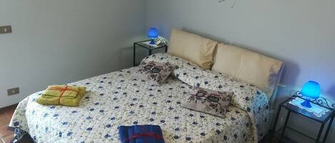 A bedroom with a bed, two bedside tables, a lamp, and a wall decoration.