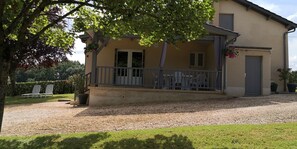 A two-story building with a balcony, a gravel driveway, and a grassy lawn.