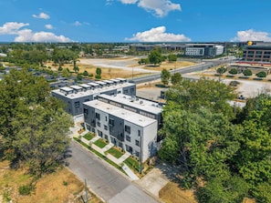 A modern multi-story building with a flat roof, surrounded by trees and a parking lot. - The Lightwell- Garage - 0.5 mi DT (Bentonville)