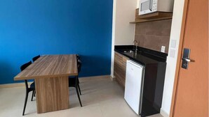 Una cocina compacta equipada con microondas, refrigerador y una mesa de comedor de madera con sillas.