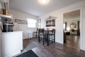 A compact kitchen with a dining area, a white refrigerator, a coffee maker, and a wall-mounted picture frame. - Downtown Indy Studio apartment (Indianapolis)