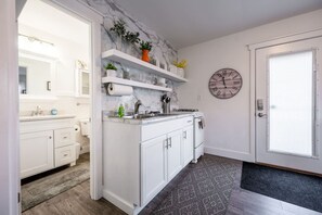 A kitchen with white cabinets, a marble backsplash, and a clock on the wall. - Downtown Indy Studio apartment (Indianapolis)