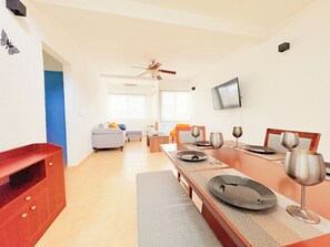 A modern living room with a dining area, a ceiling fan, a flat-screen TV, and a sofa. - P.H. 360° view: to the sea, Isla Mujeres and Puerto Cancun 7 min walk to the beach (Cancún)