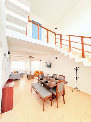 A spacious living area with a dining table, sofas, and a staircase. - P.H. 360° view: to the sea, Isla Mujeres and Puerto Cancun 7 min walk to the beach (Cancún)