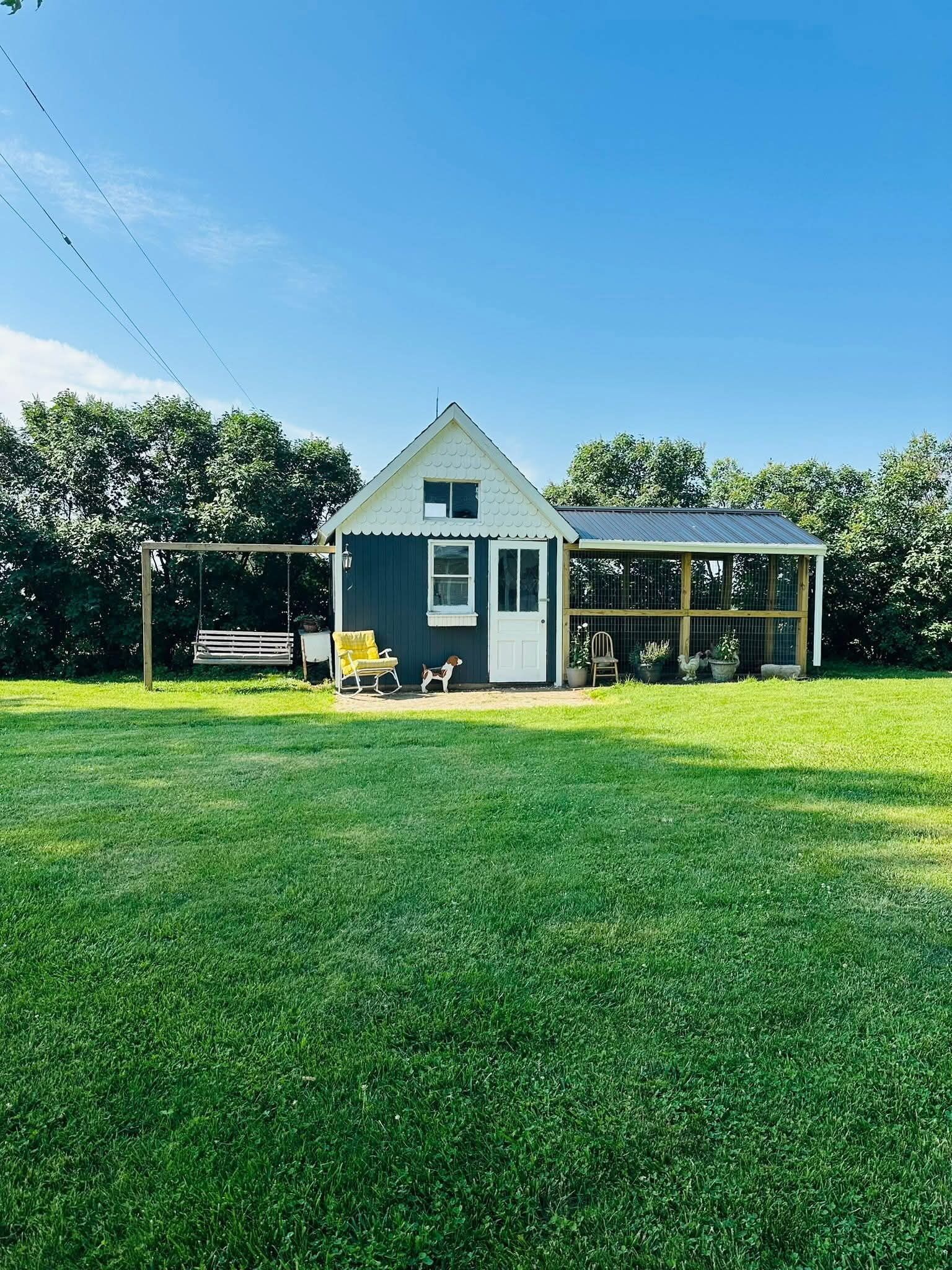 Ein Haus mit überdachter Veranda, einem kleinen Hund und einer Schaukel.