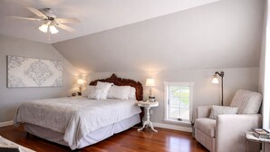 Une chambre avec un grand lit, une tête de lit en bois, une table de chevet, une lampe, une chaise et une fenêtre donnant sur un beau paysage.