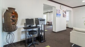 A reception area with a desk, computer, printer, and a decorative vase. - Everstay Living Extended Stay (Plano)