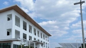 A multi-story building with a flat roof, large windows, and a covered entrance area.