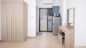 A modern, minimalistic room with a wardrobe, a kitchenette, and a mirror.