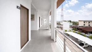 A corridor with doors numbered 302, leading to a balcony with a view of buildings and a tower.