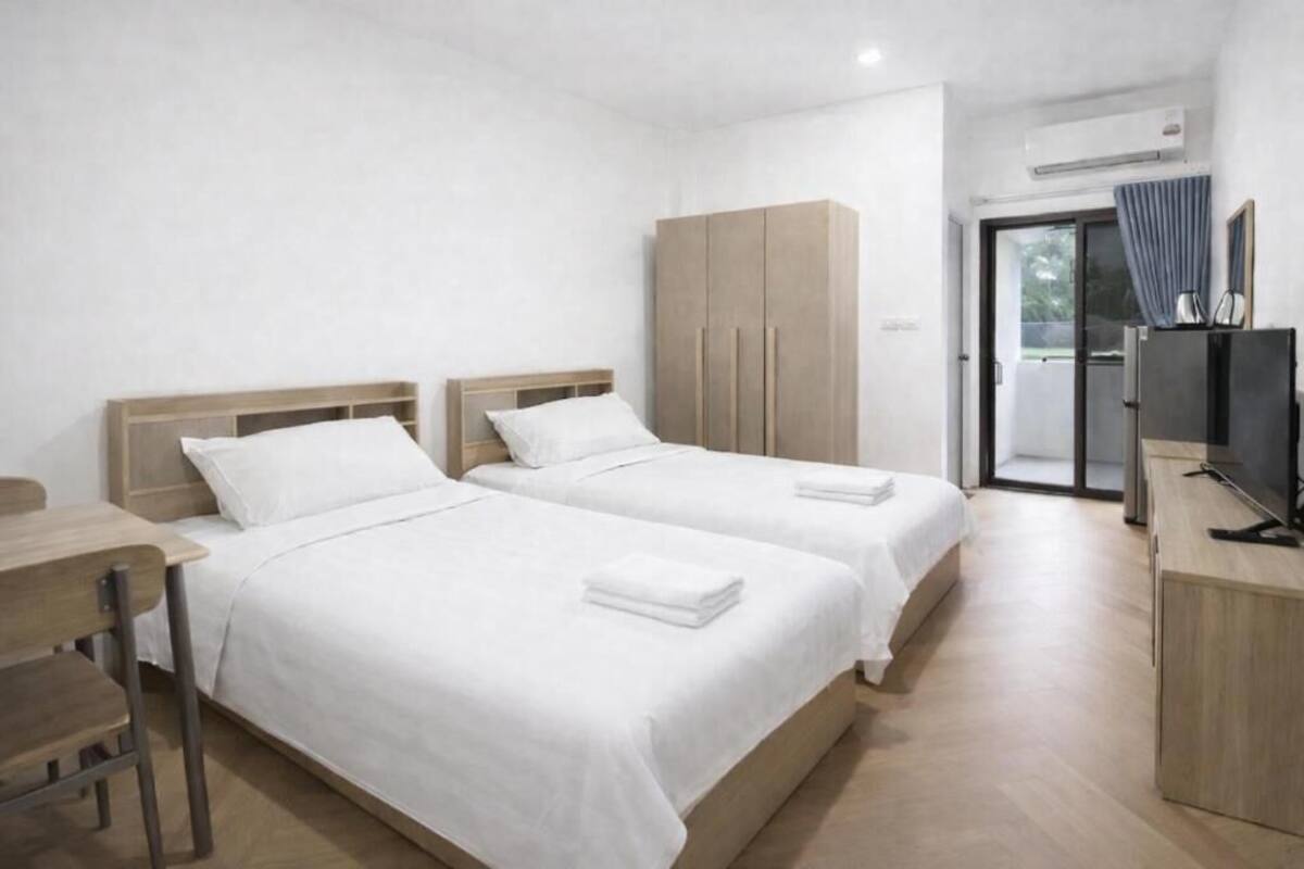 Una habitación de hotel con dos camas, un escritorio, un armario y un televisor.