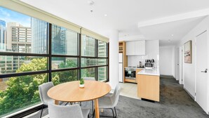 Un appartement moderne doté d’une cuisine, d’un coin repas et de grandes fenêtres offrant une vue sur la ville.