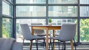 Une salle de réunion moderne avec une table en bois, quatre chaises grises et une plante en pot.