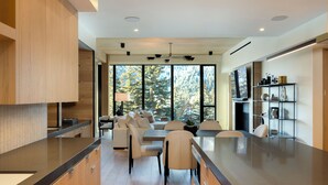 A modern kitchen with a large island, wooden cabinets, and a dining area with a sofa and chairs. - Modern Luxury in Downtown Ketchum (Ketchum)