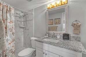 A bathroom with a shower, toilet, sink, and vanity.