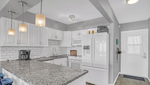 A modern kitchen with white cabinets, granite countertops, and stainless steel appliances. - INCREDIBLE! Oceanfront Dream Escape! Unit 21 is a Rare 3-Bedroom Condo! (Cocoa Beach)