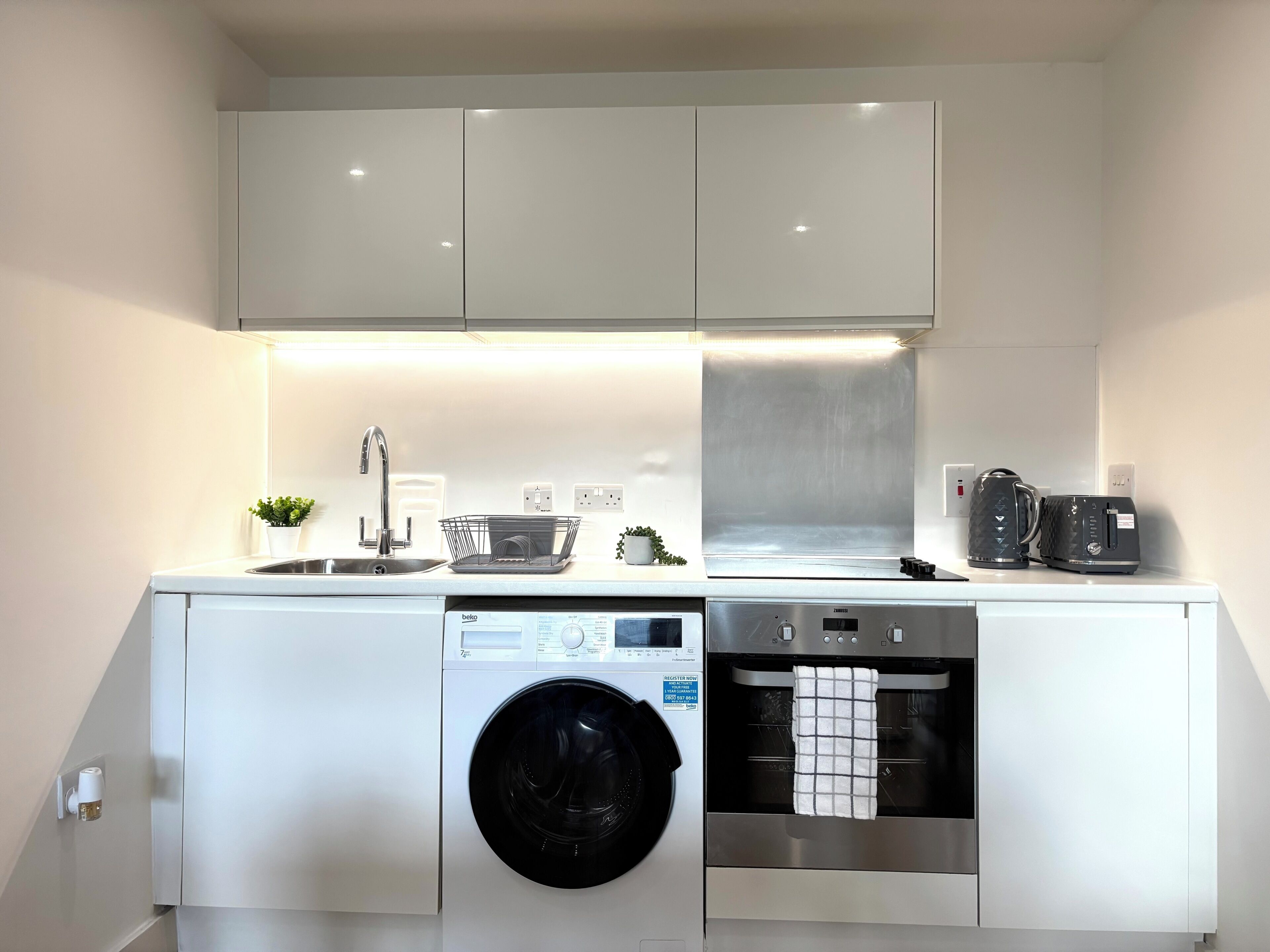 A compact kitchen with a washing machine, dishwasher, and oven.