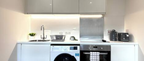 A compact kitchen with a washing machine, dishwasher, and oven.