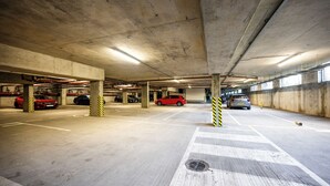En parkeringskælder med støttepelere af beton, afmærkede parkeringspladser og et fodgængerfelt.