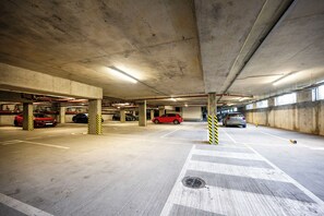 Un aparcament subterrani amb pilars de formigó, places d'aparcament senyalitzades i un pas de vianants.