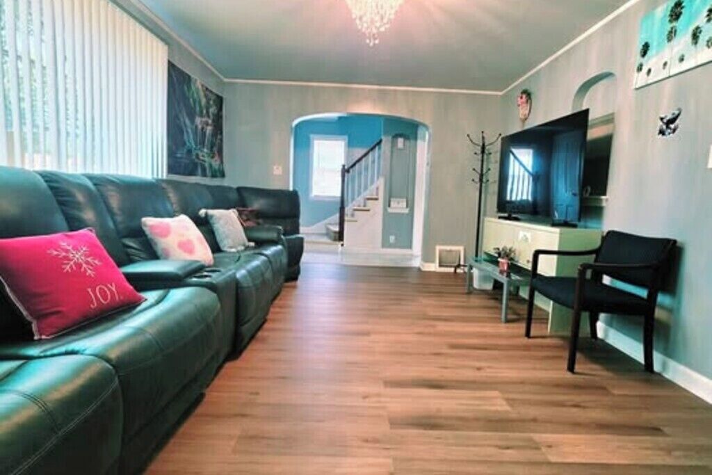 A living room with a sofa, a television, and a staircase leading to another room.