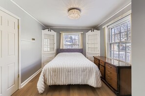A bedroom with a bed, dresser, and window. - Spacious 4-bedroom house in beautiful Milwaukee with AC (Milwaukee)