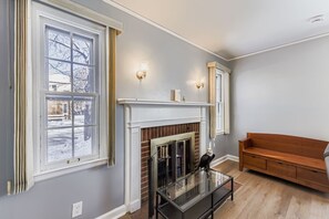 A room with a fireplace, a bench, and a window with a view of a snowy landscape. - Spacious 4-bedroom house in beautiful Milwaukee with AC (Milwaukee)